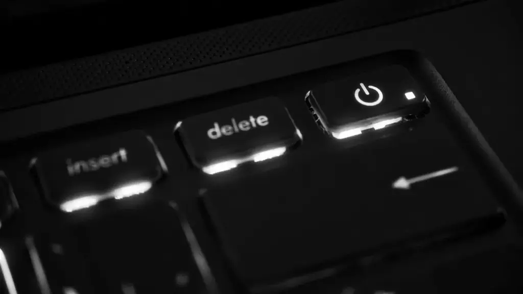 Leuchtende Einschalttaste eines Laptops im Dunkeln