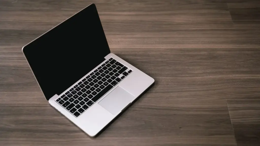 Ausgeschalteter Laptop mit schwarzem Bildschirm auf einem Holztisch